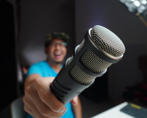 man in blue and black crew neck t-shirt holding microphone