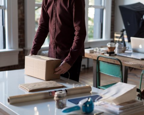 person holding cardboard box on table