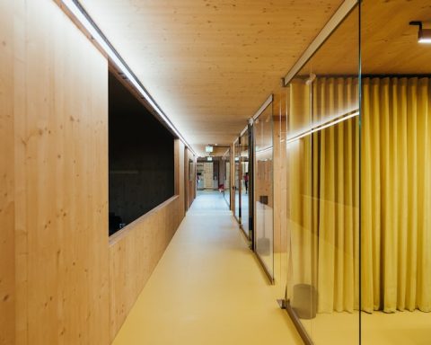 a long hallway with wooden walls and yellow curtains