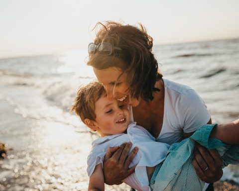 photo of mother and child beside body of water