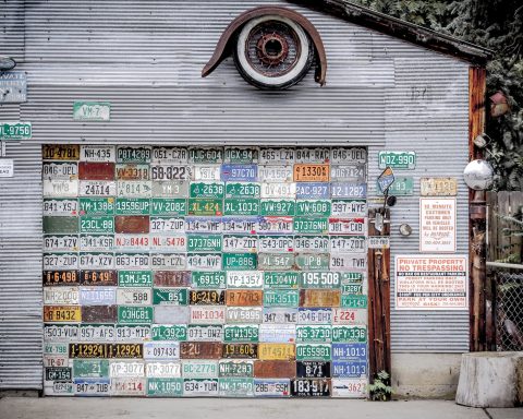 assorted license plates hanging on gray wall