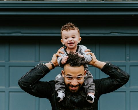 man in black leather jacket carrying boy in black leather jacket