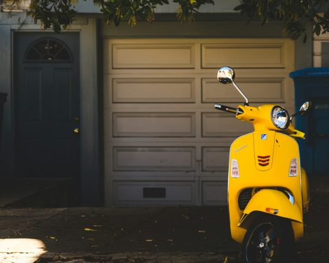 yellow motor scooter parked near white garage door