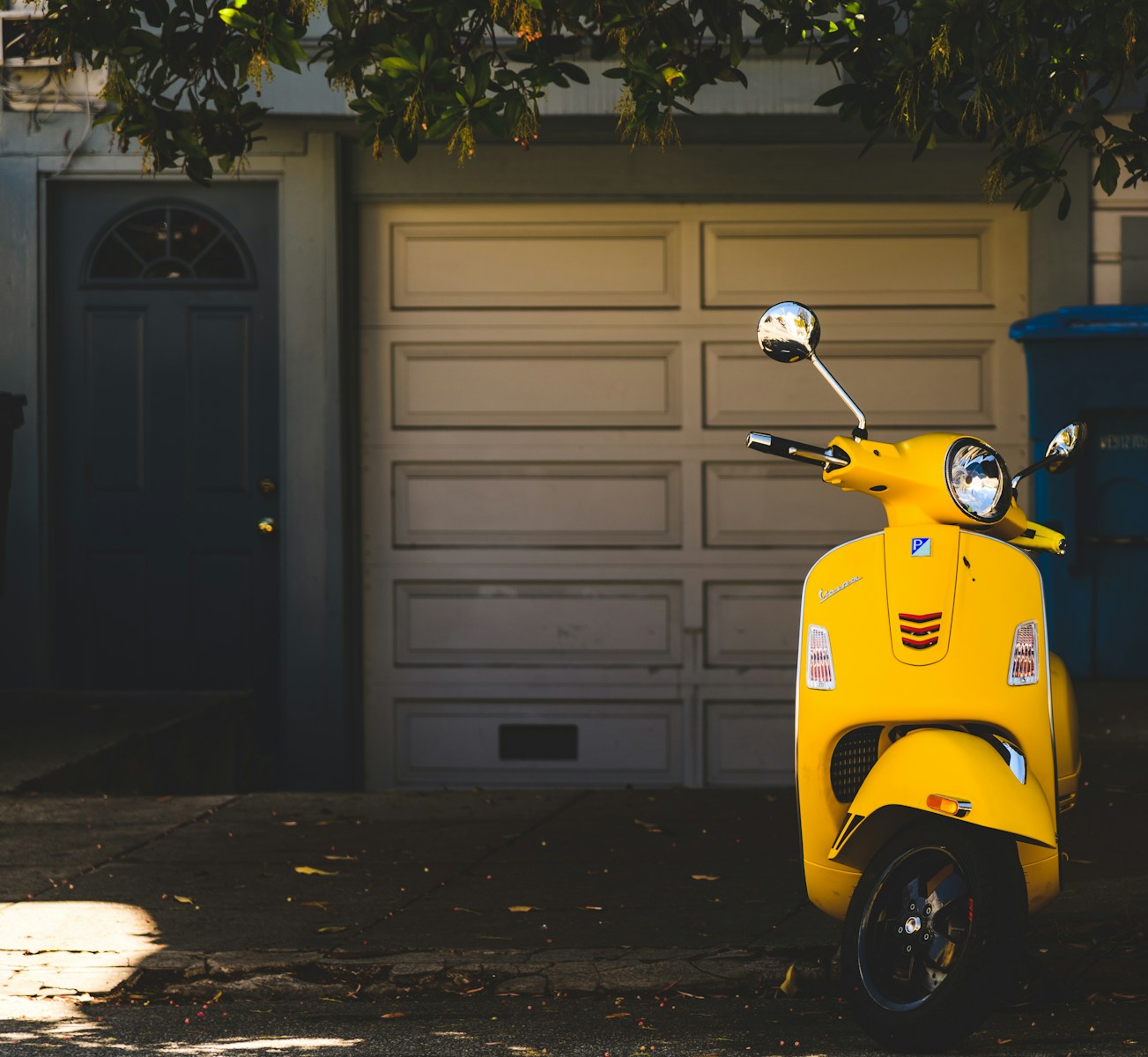 yellow motor scooter parked near white garage door