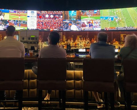 a group of people sitting at a bar watching tv