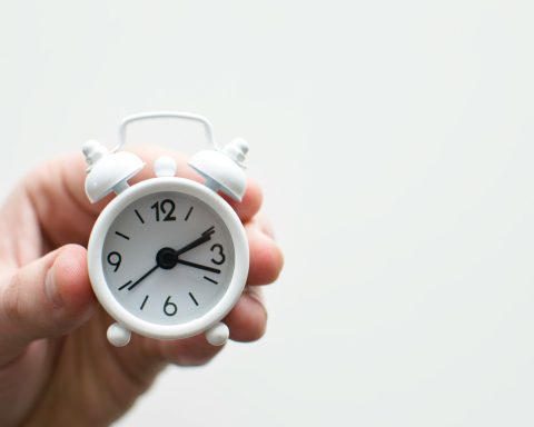 person holding white mini bell alarmclock