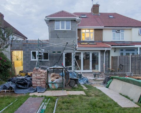 A suburban house undergoing major renovations with scaffolding and building materials.