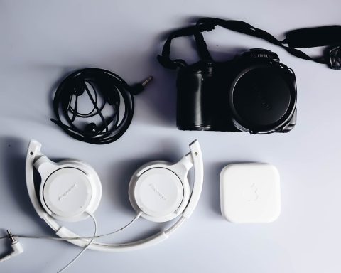 black Fujifilm DSLR camera and white corded headphones