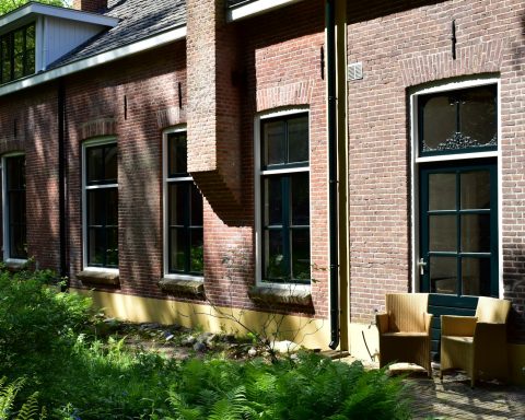 a brick building with lots of windows and a bench in front of it