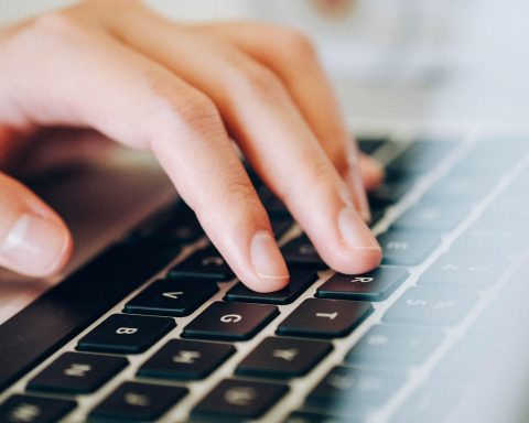 Data engineer werkt achter een laptop met code en datavisualisaties op het scherm