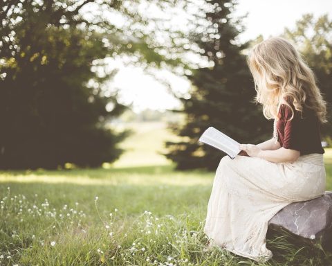 Een vrouw leest een oud Nederlands boek, verwijzend naar de rijke geschiedenis van vrouwelijke schrijfsters in Nederland