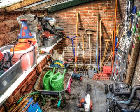 Tuingereedschap netjes opgehangen aan de muur van een schuur, klaar voor de winter