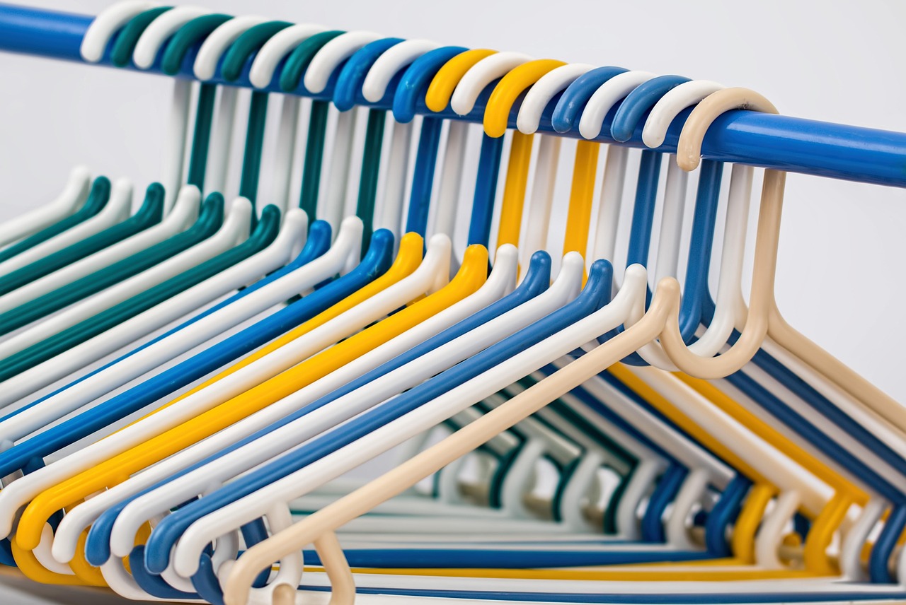 Een overzichtelijke kledingkast met een kleine, geordende collectie neutrale kledingstukken op hangers