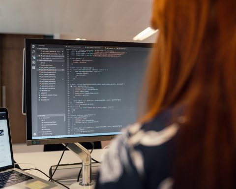 Twee developers in gesprek op kantoor, één wijst naar een scherm met code